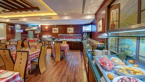 Ein Restaurant mit Holzboden, karierten Tischdecken und einem Buffet mit verschiedenen Speisen.