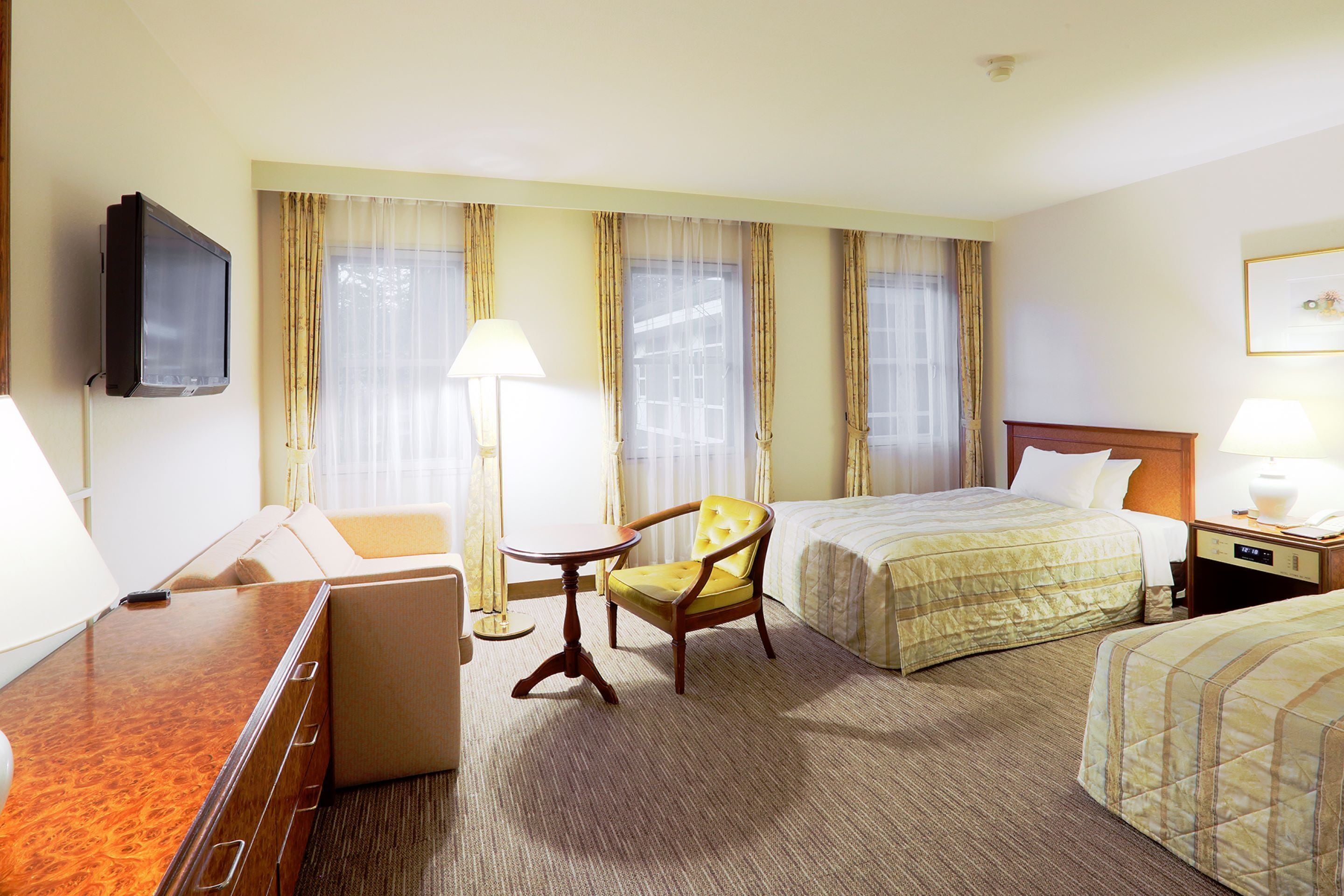 A hotel room with a bed, a chair, a desk, and a television.