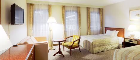 A hotel room with a bed, a chair, a desk, and a television.