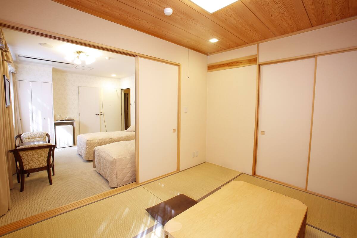 Una stanza tradizionale giapponese con pavimento in tatami, un futon, una scrivania in legno e una sedia.