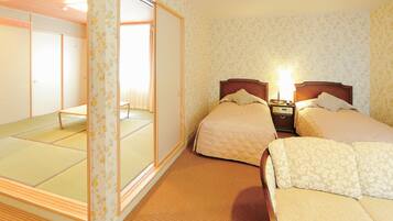 A hotel room with two beds, a wooden floor, and a sliding door leading to a tatami mat area.