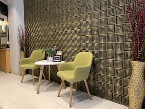 A modern interior with two green chairs around a small table, a patterned wall, and decorative plants. - The Vibe Inn (Yangon)