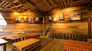 A rustic wooden interior with high ceilings, wooden benches, and tables.