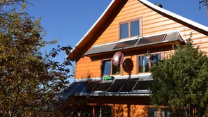 A wooden cabin with a sloped roof, solar panels, and a large window. - MSC Apartments Honeymoon (Zakopane)
