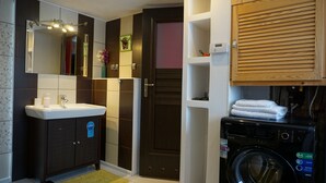 A compact bathroom with a sink, mirror, and a washing machine. - MSC Apartments Honeymoon (Zakopane)