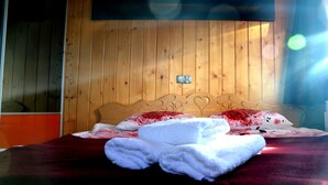 A wooden-paneled room with a bed, a thermostat, and a window. - MSC Apartments Honeymoon (Zakopane)