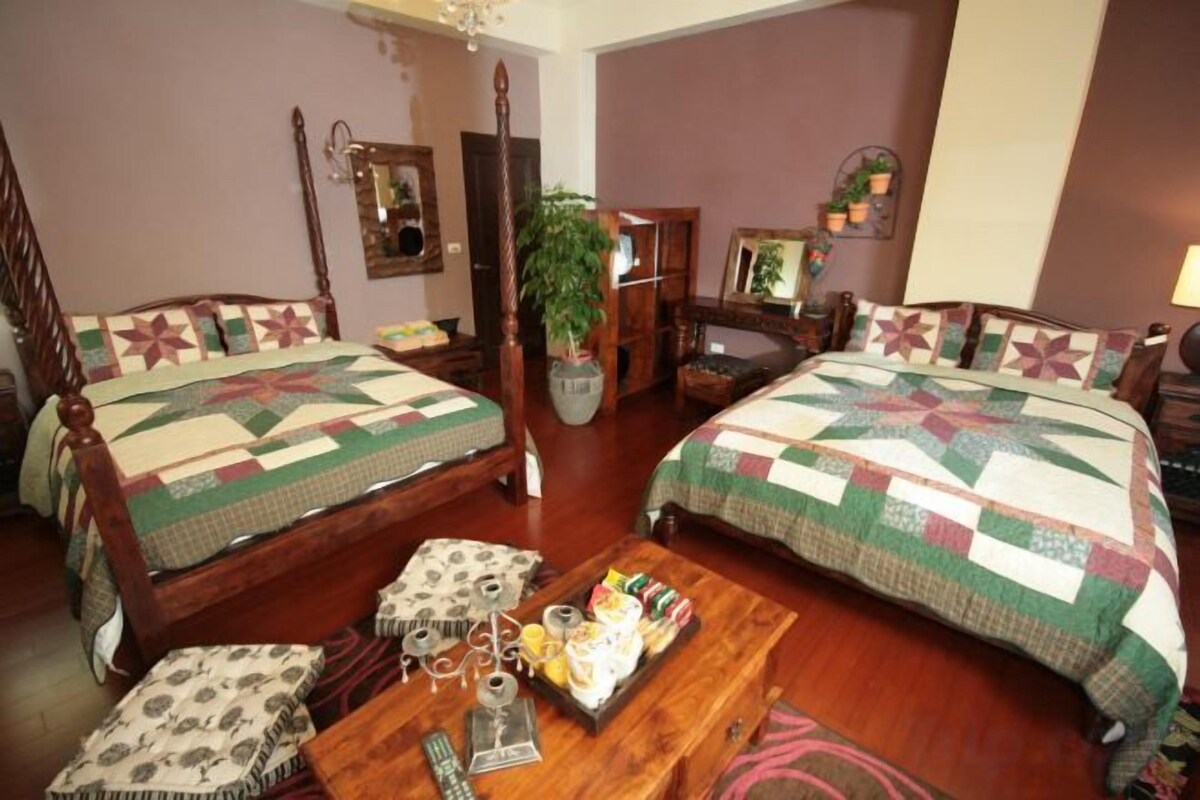 Una habitación con dos camas de madera, una mesa de madera con una bandeja de objetos y una planta en maceta.