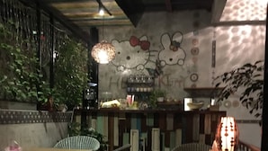 A dimly lit restaurant interior with a bar area, wicker furniture, and a decorative wall with a Hello Kitty motif. - Hualien Paris Home B&B (Hualien City)