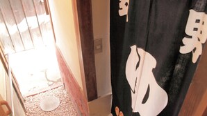 A narrow hallway with a wooden door and a black curtain with white patterns. - Wakayama Guest House Shido (Hashimoto)