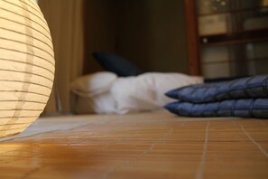 A wooden floor with a patterned rug and pillows on a bed. - Wakayama Guest House Shido (Hashimoto)