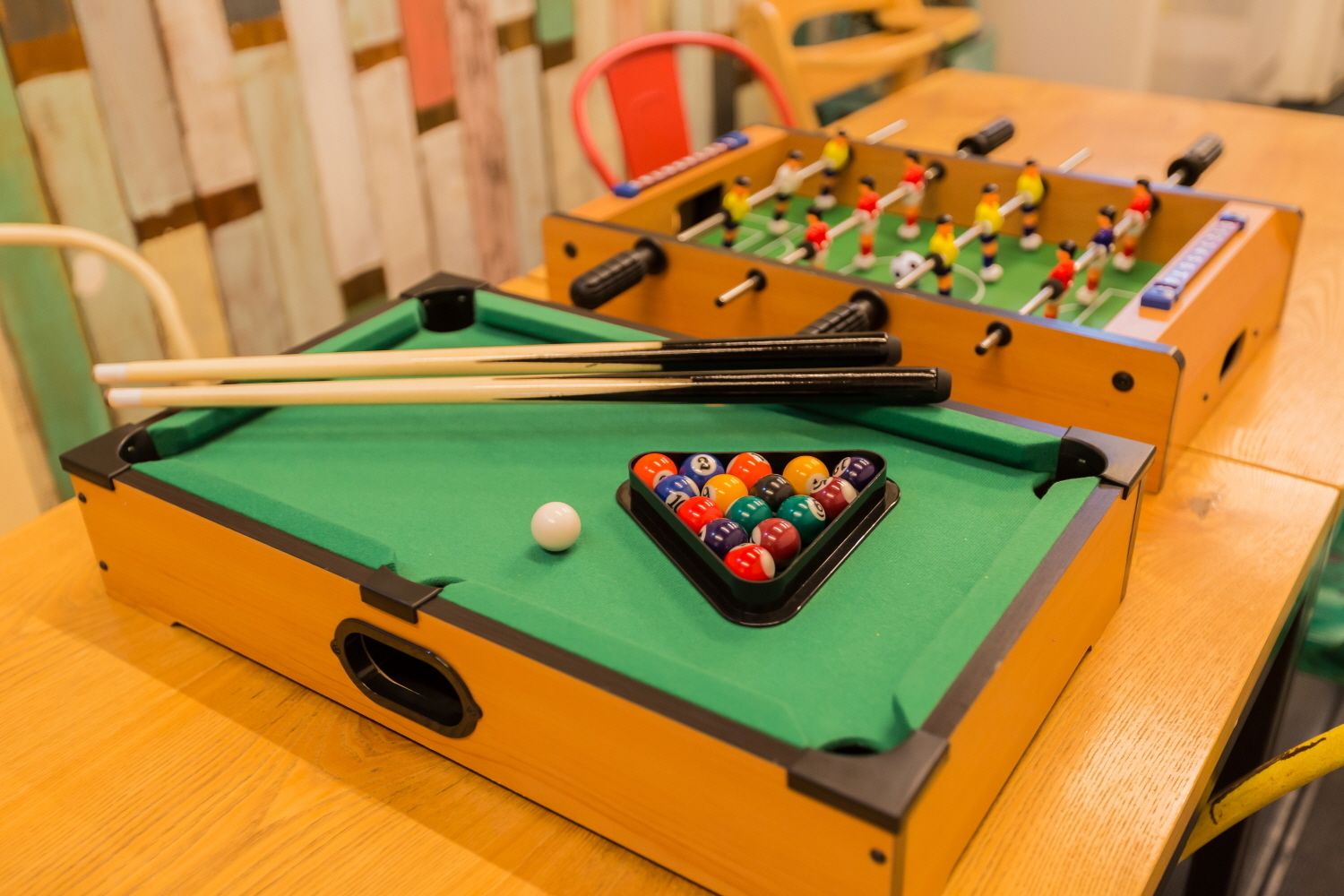 A pool table with a green felt surface, a set of pool cues, and a rack of billiard balls.