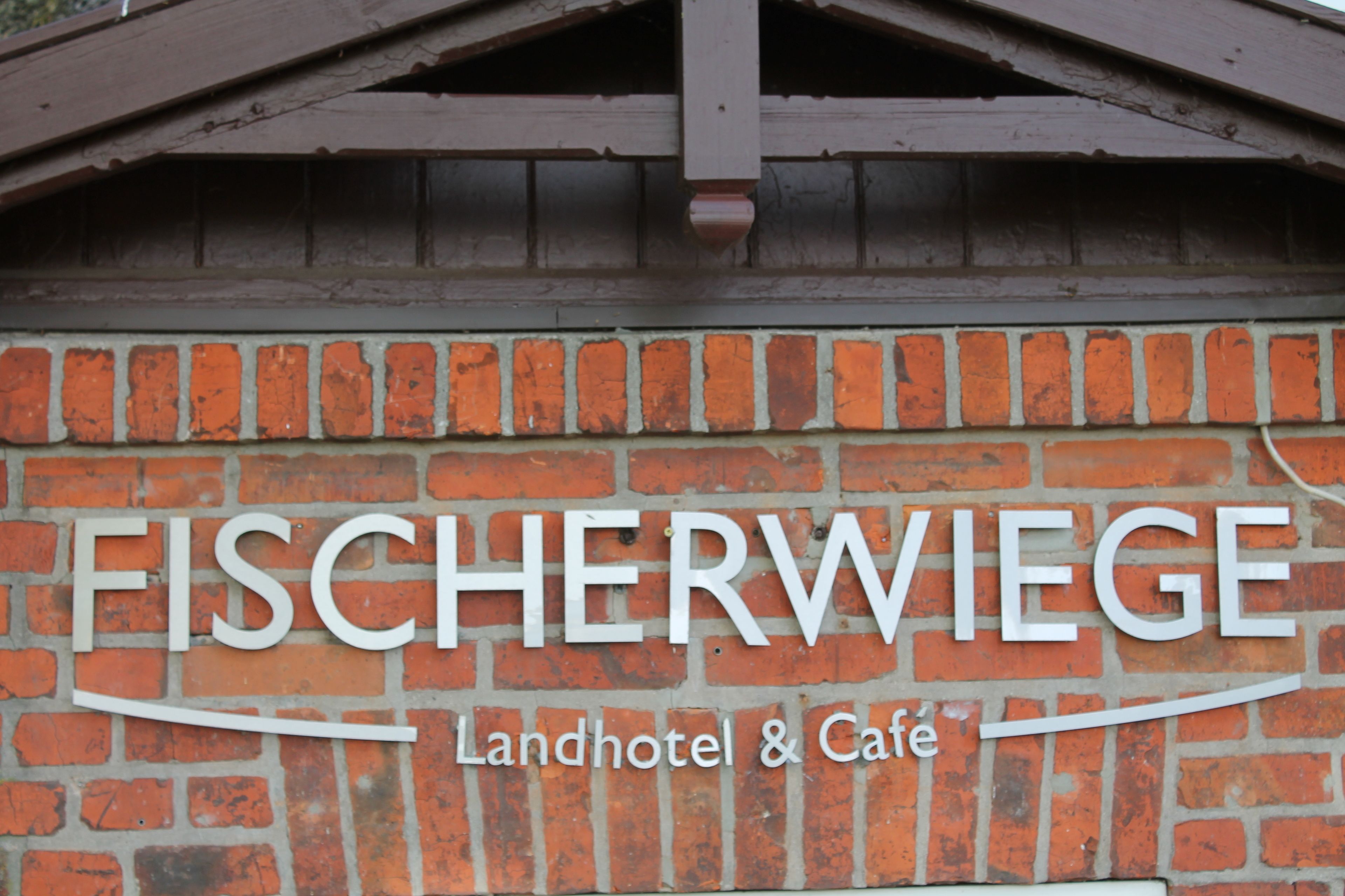 Un muro de ladrillo con el letrero "FISCHERWIEGE Landhotel & Cafe".
