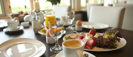 Una escena de desayuno con platos, tazas y diversos alimentos sobre una mesa.