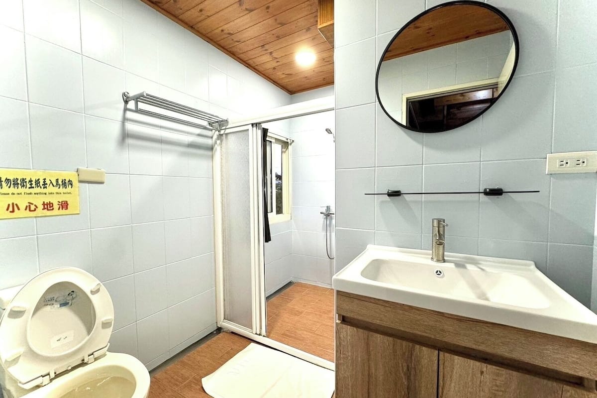 A bathroom with a toilet, shower, sink, and mirror.