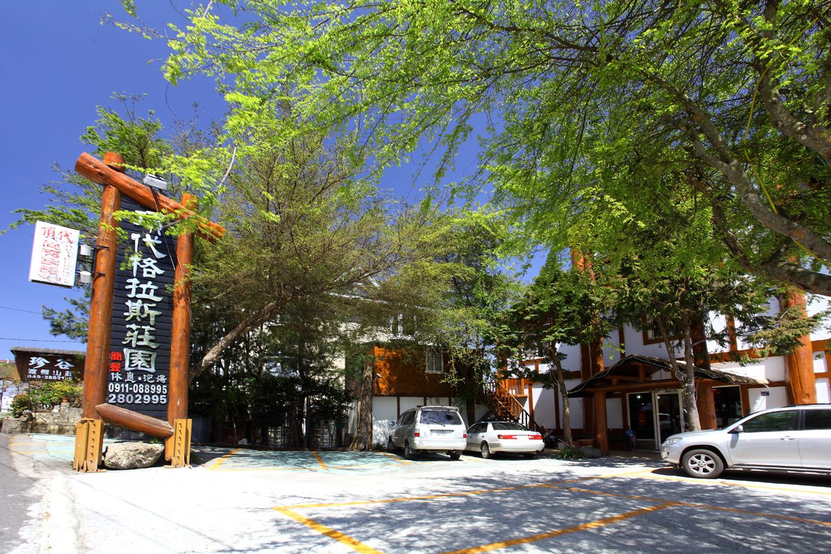 A traditional Japanese building with a wooden signpost and parked cars in front.