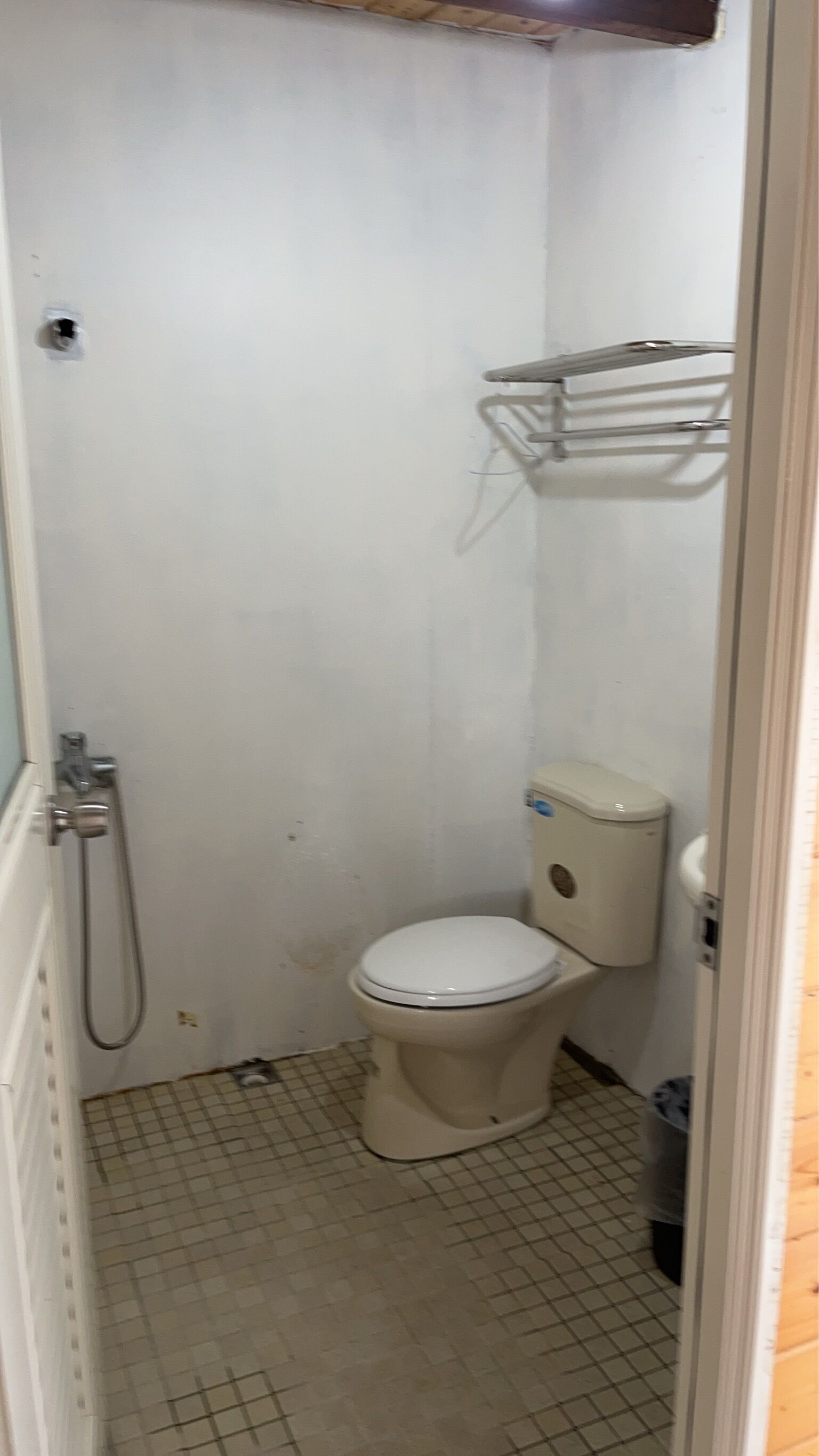 A small, narrow bathroom with a toilet, a shower, and a towel rack.