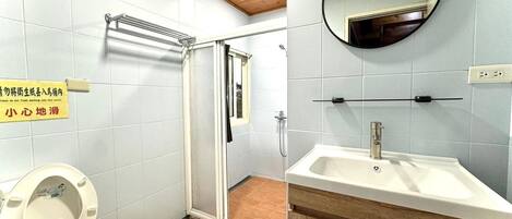 A bathroom with a toilet, shower, and sink.