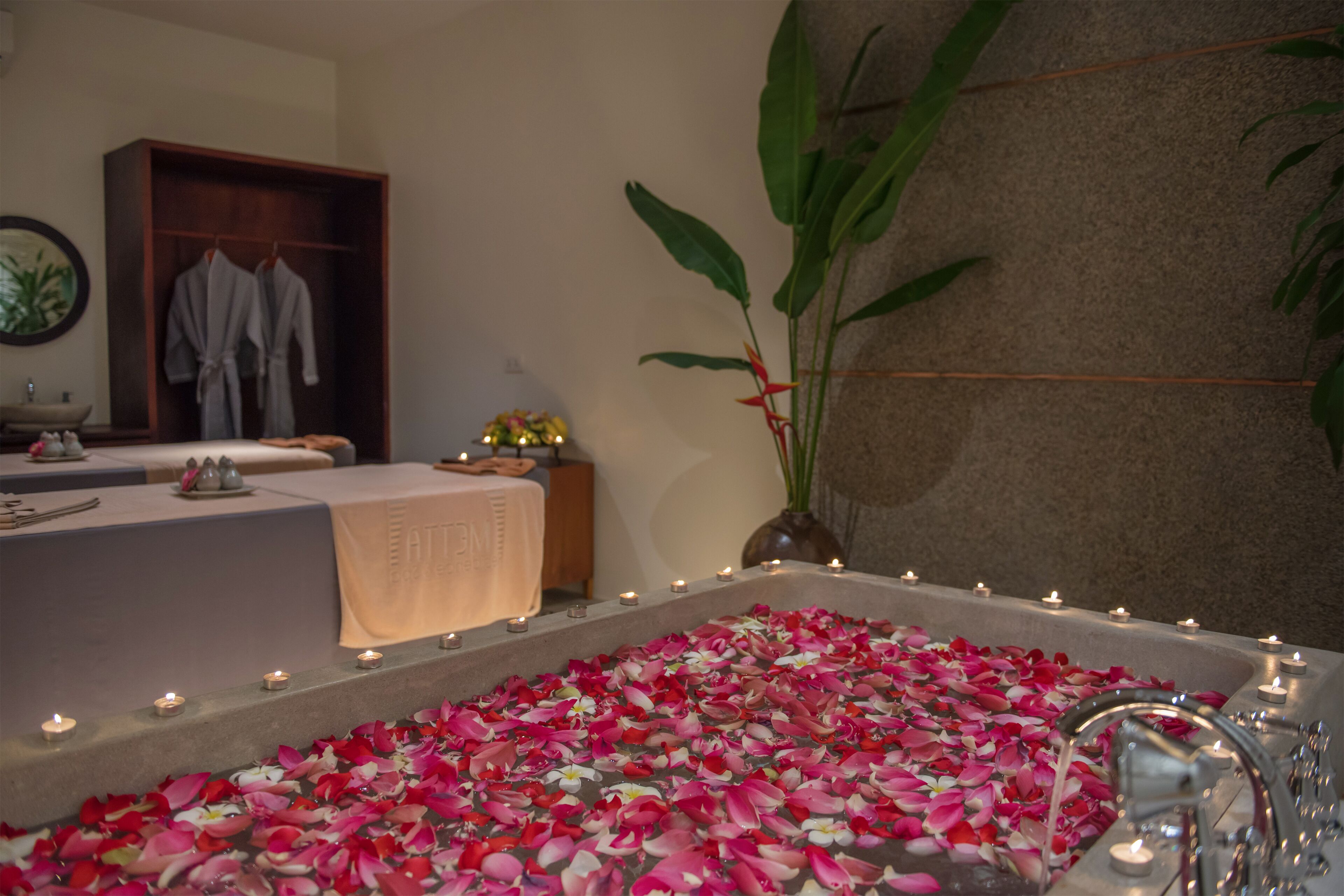 Ein Badezimmer mit einer Badewanne, die mit Rosenblüten gefüllt ist, einem Waschbecken und einem Spiegel.