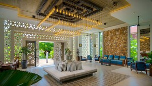 A spacious living area with a modern sofa, blue and white patterned floor, and a stone wall. - Metta Residence & Spa (Siem Reap)
