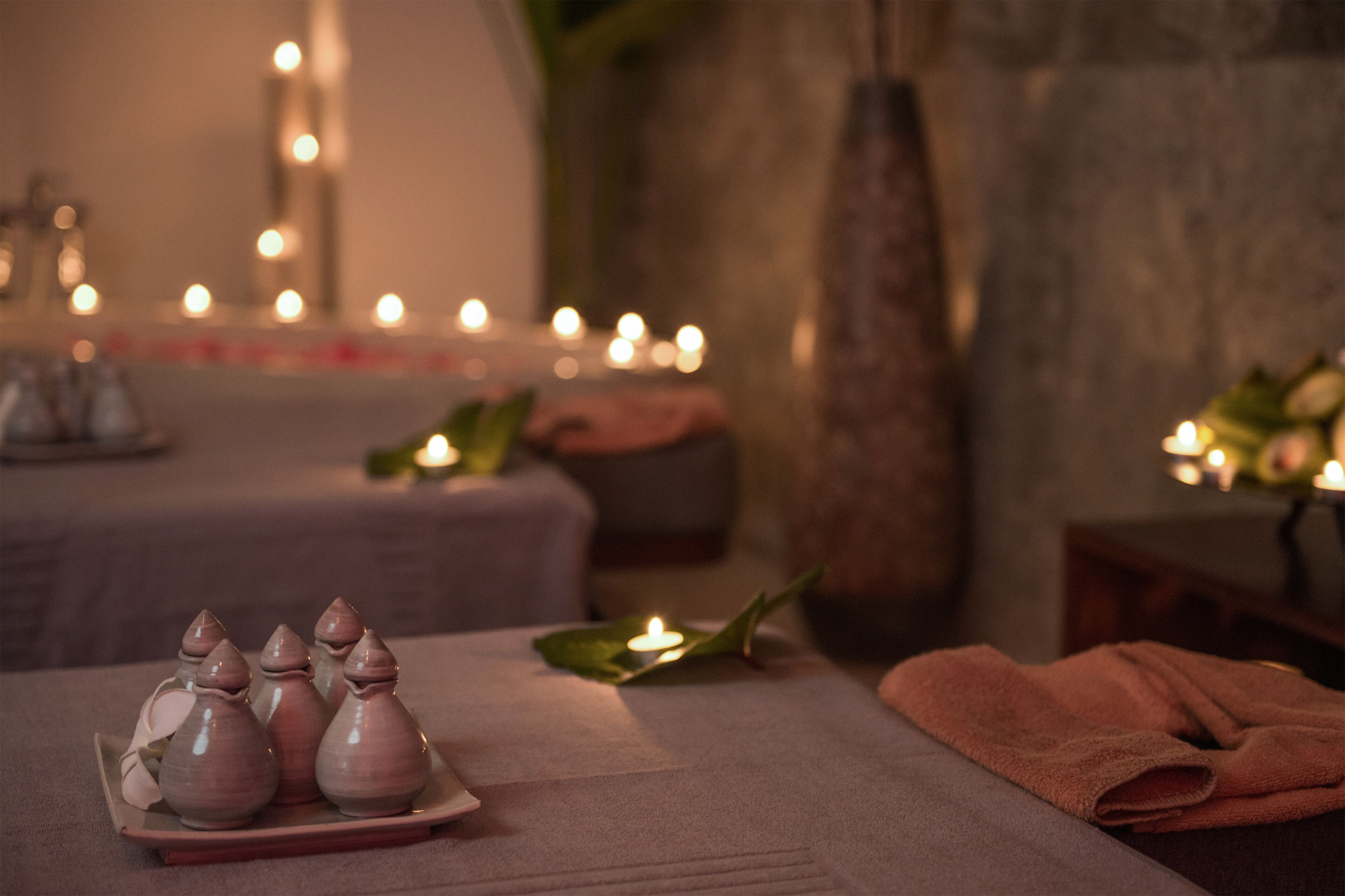 A spa setting with candles, a vase, and a towel on a table.