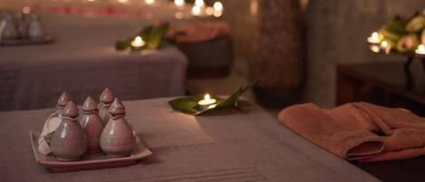 A spa setting with candles, a vase, and a towel on a table.