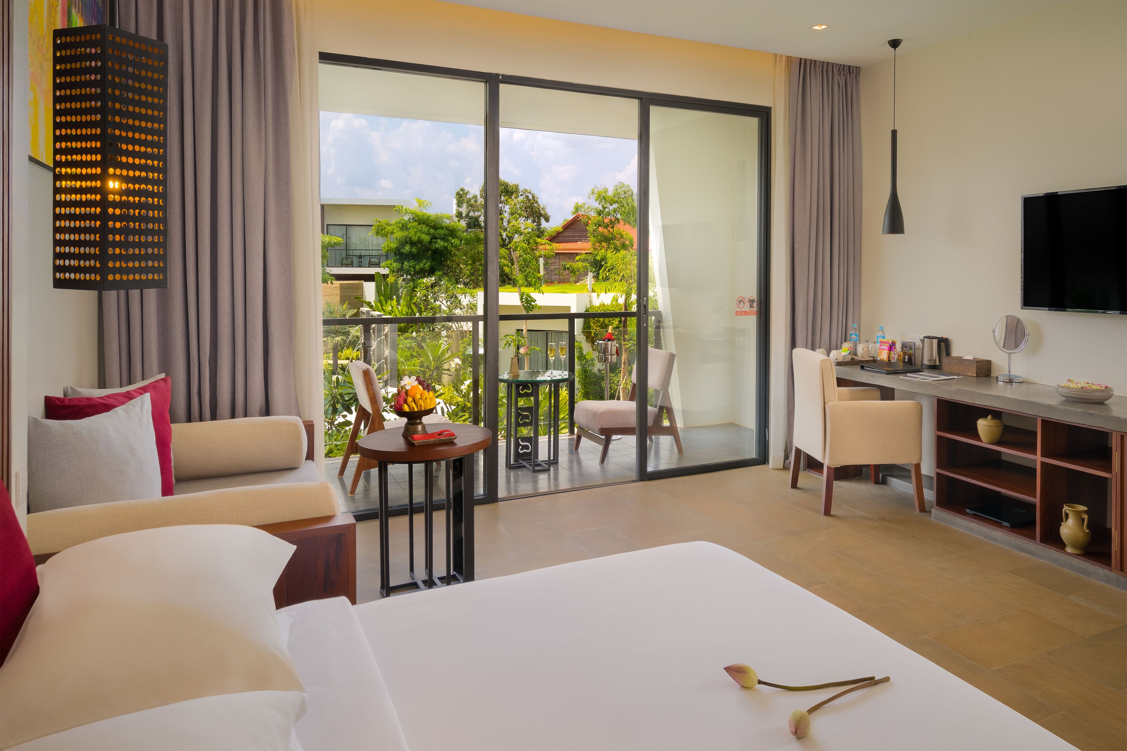 Habitación de hotel con una cama grande, un escritorio, una silla y un balcón con vistas al exterior.