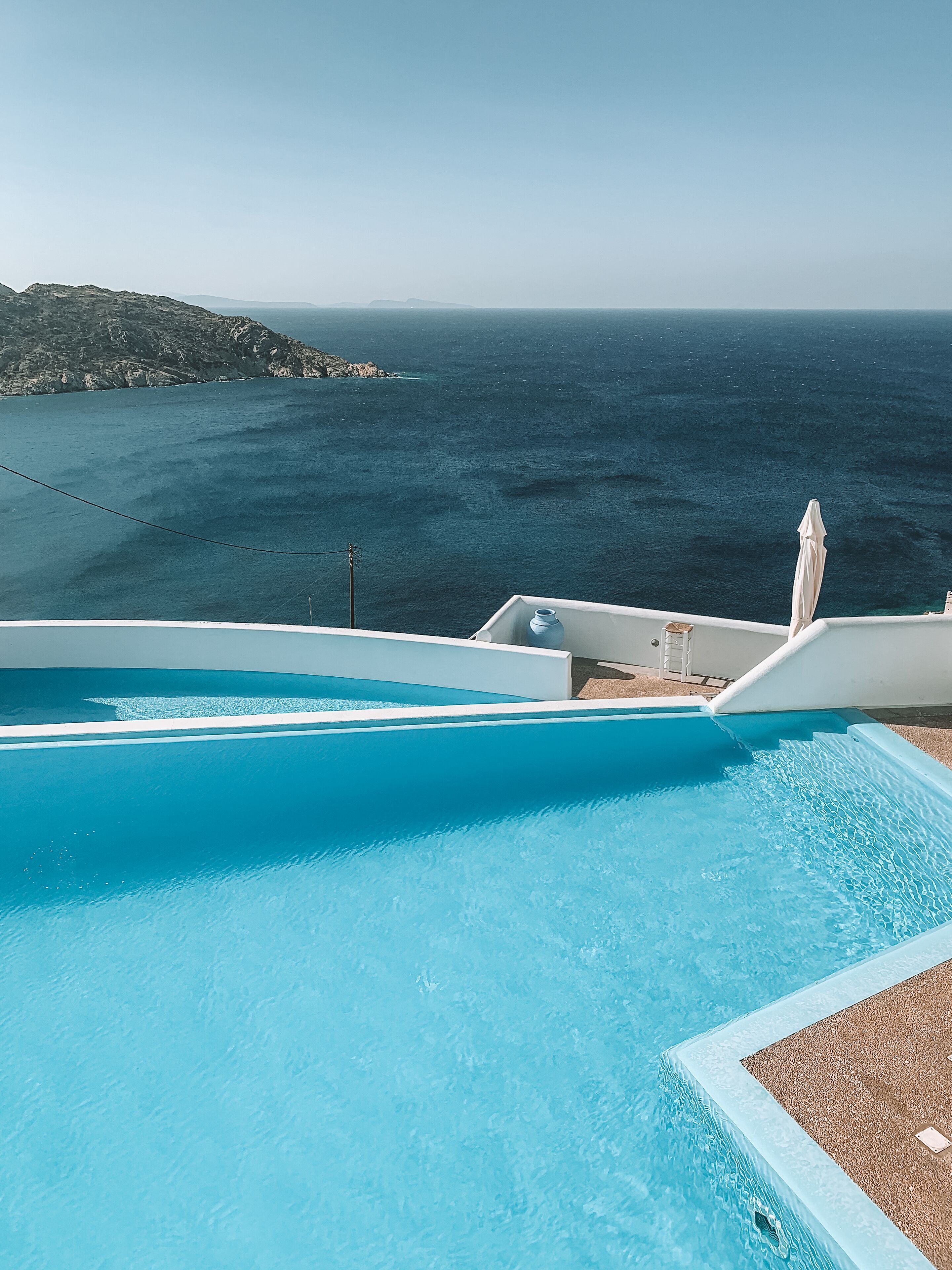A pool with a view of the ocean and a rocky landscape.