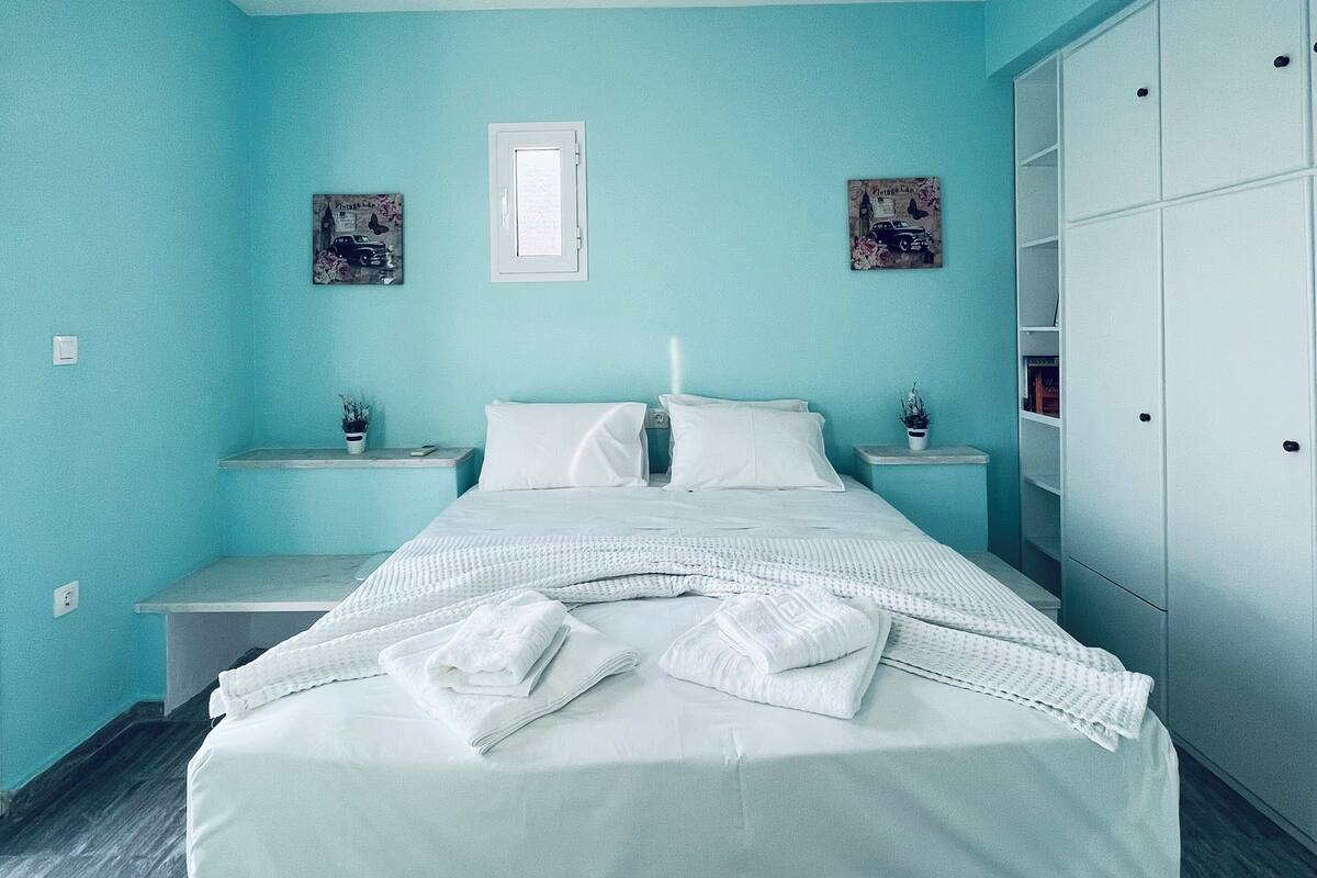 A bedroom with a bed, nightstands, a wardrobe, and a window.