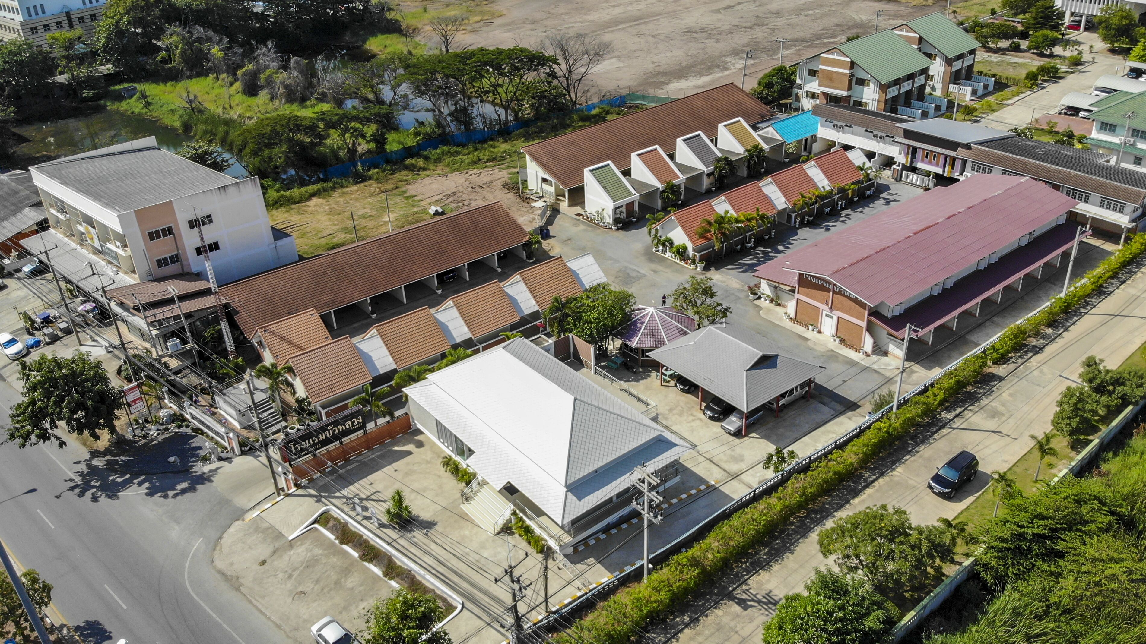 An aerial view of a commercial area with multiple buildings, including a large warehouse with a red roof and a smaller building with a green roof.