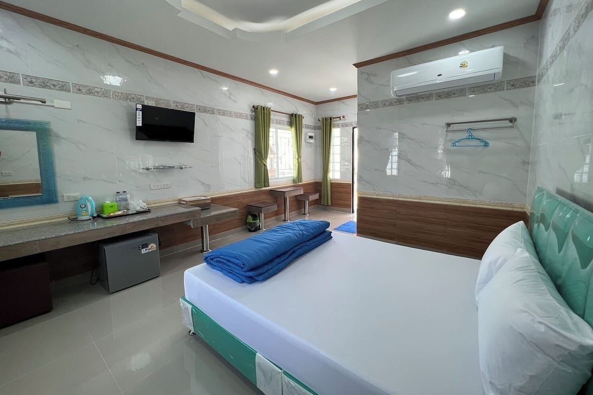 Una habitación de hotel con cama, televisión, escritorio pequeño, espejo y baño.