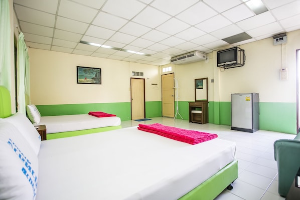 Una habitación de hotel con cama, escritorio, silla, televisor y refrigerador.