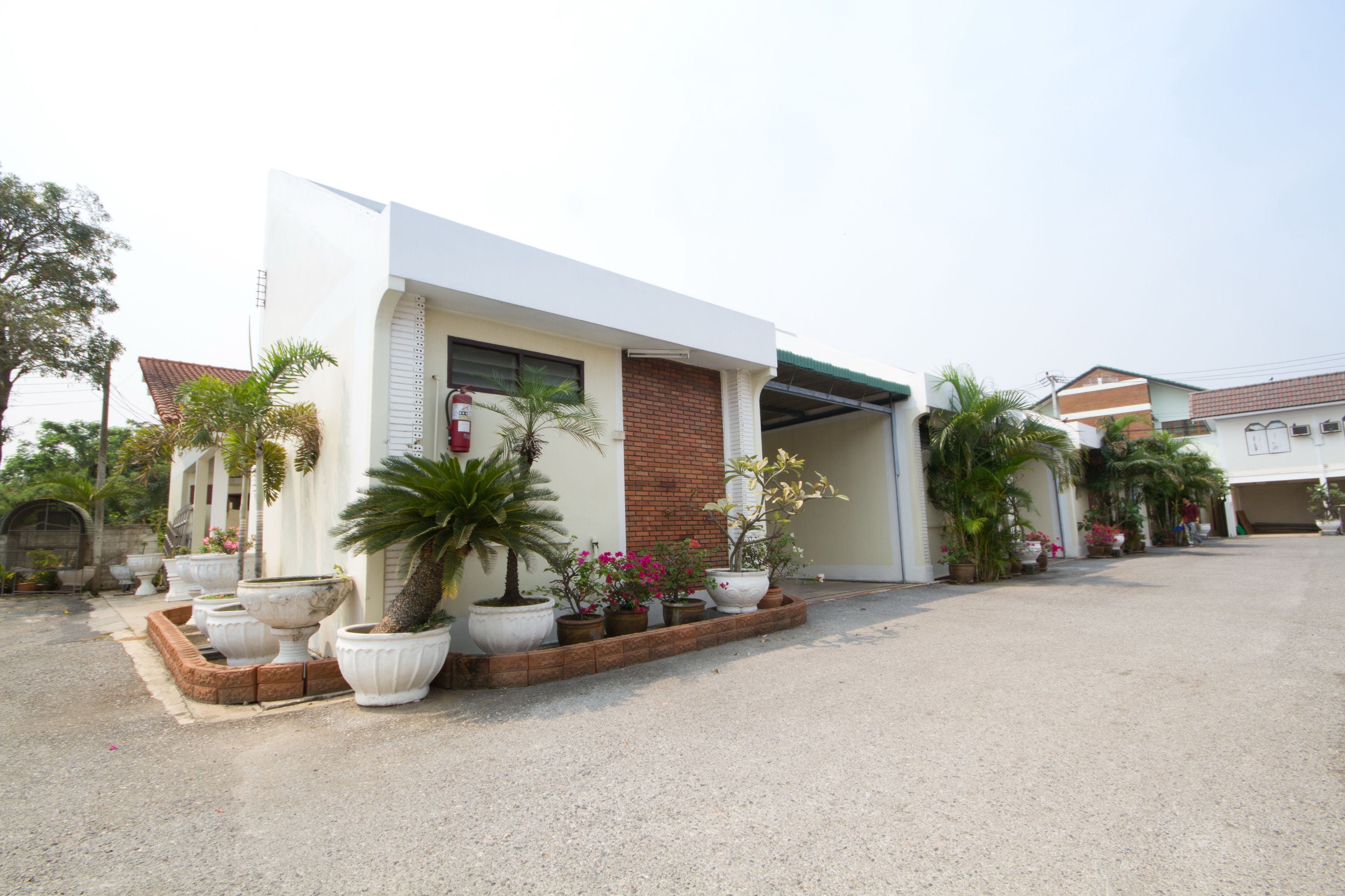 A modern building with a white facade, a brick entrance, and a covered driveway.