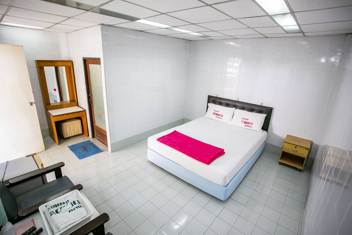 Una habitación de hotel con una cama, una mesita de noche de madera, un escritorio y una silla.