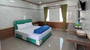 Una habitación de hotel moderna con una cama grande, una tocador con espejo y un televisor montado en la pared.