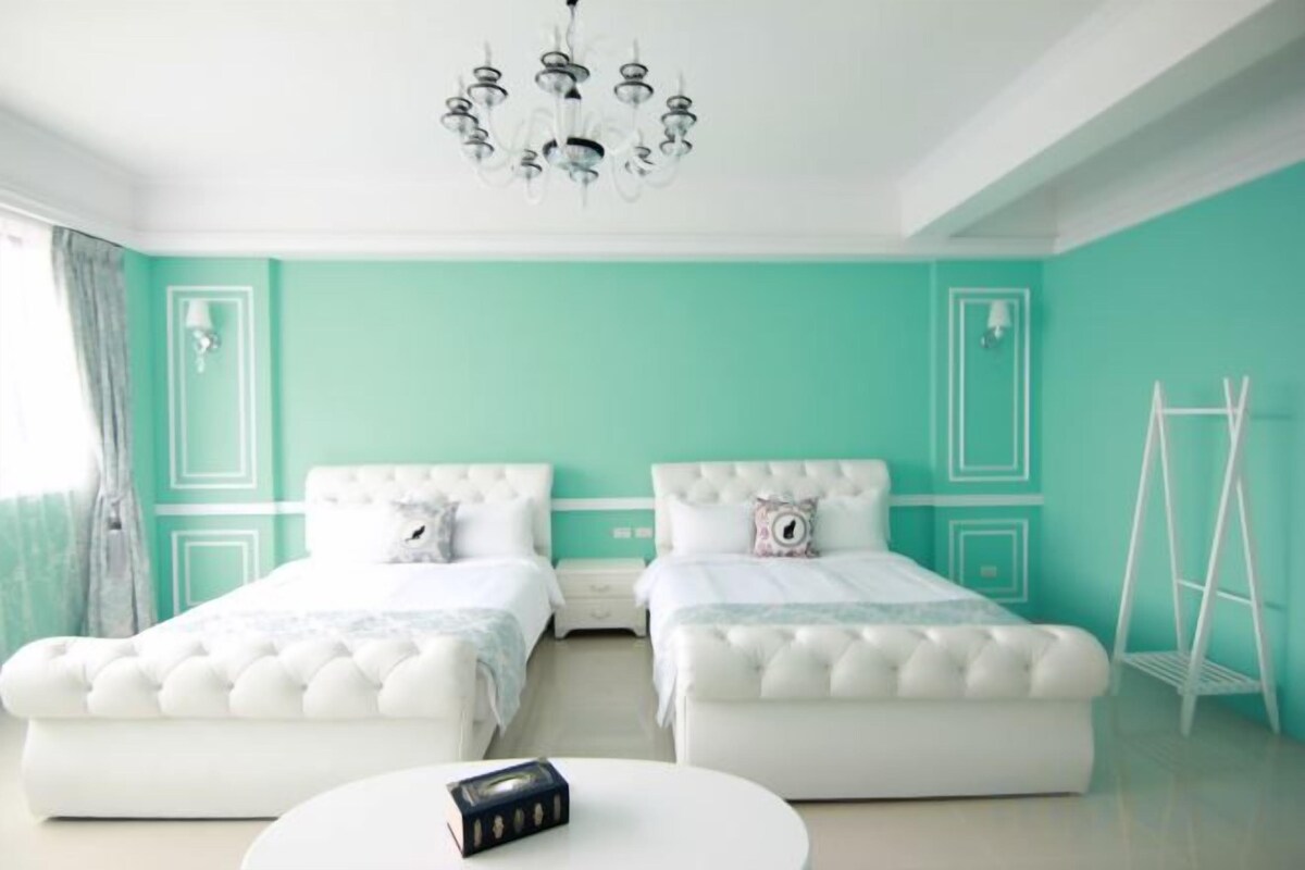A bedroom with two beds, a white round table, and a chandelier.
