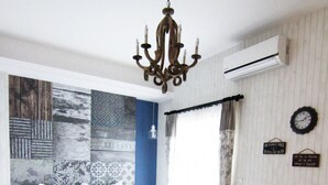 A bedroom with a bed, a dark armchair, a small table, and a chandelier.