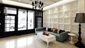 A modern living room with a blue sofa, white coffee table, and decorative lamps.