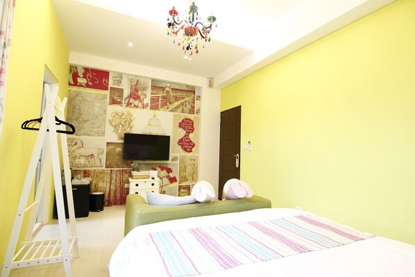 A bedroom with a bed, a dresser, a TV, and a wall decorated with various pictures and posters. - Mieh's Inn (Hualien City)