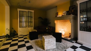 A room with a checkered floor, a fireplace, a bookshelf, and a door with glass panels. - Tripel B (Bruges)
