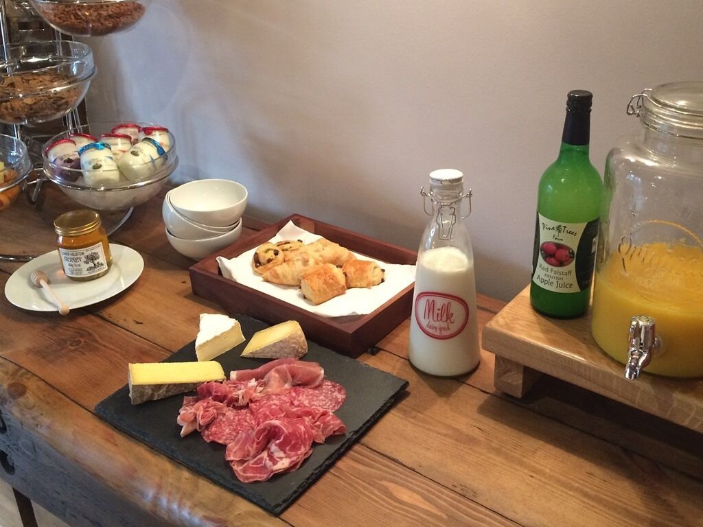 A breakfast buffet with various food items including cheese, meats, pastries, and beverages.