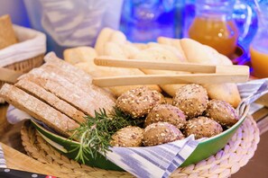 A basket of assorted breads and rolls, including whole grain and seeded varieties, on a woven mat. - Es Corte Vell - Inland Bunyola - Adults Only (Bunyola)