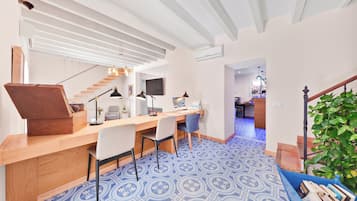 Un espace de vie moderne comprenant un bureau en bois, deux chaises, un escalier et un plancher à motifs.