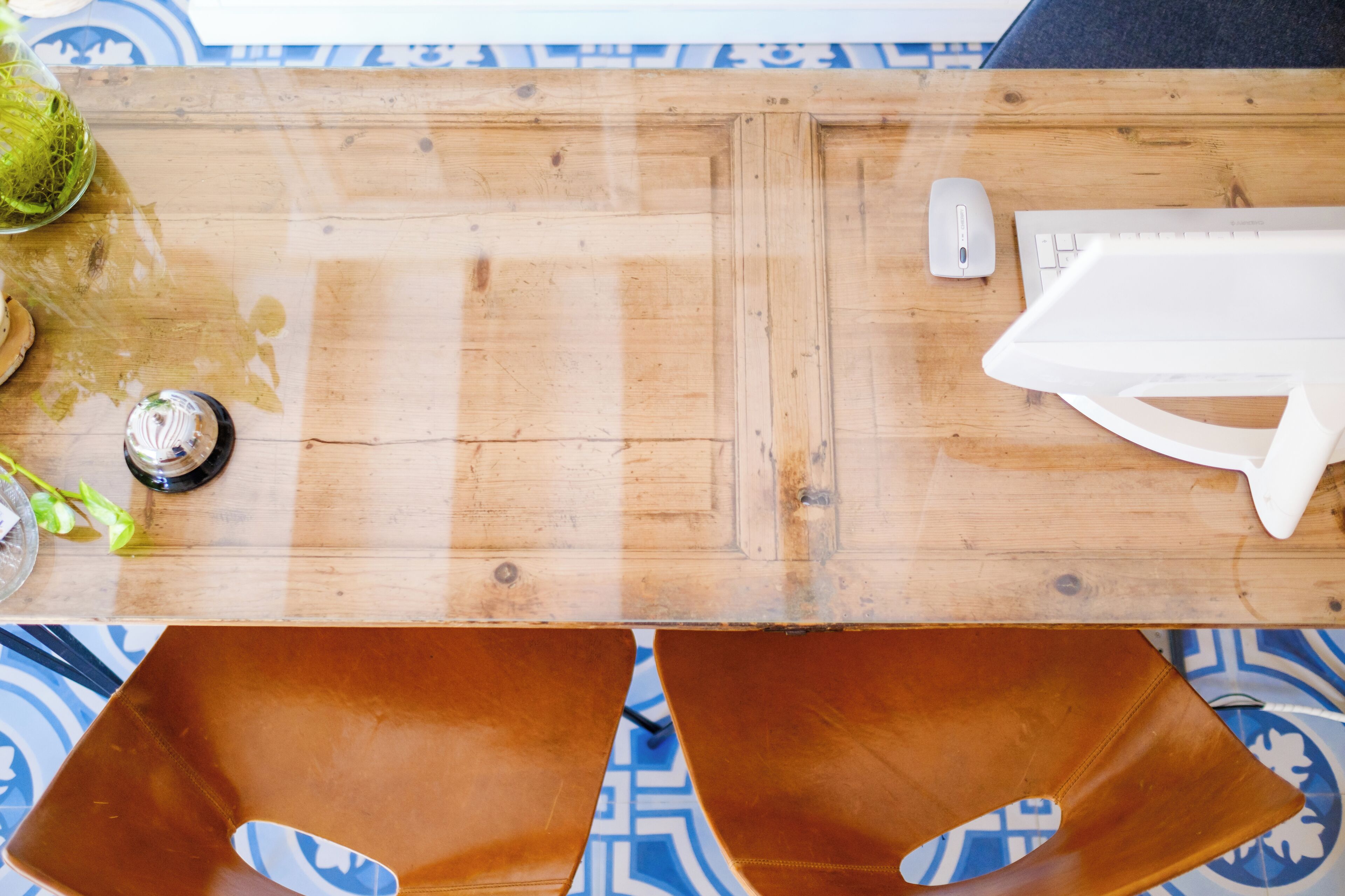Una mesa de madera con un teclado, un ratón y un objeto blanco.