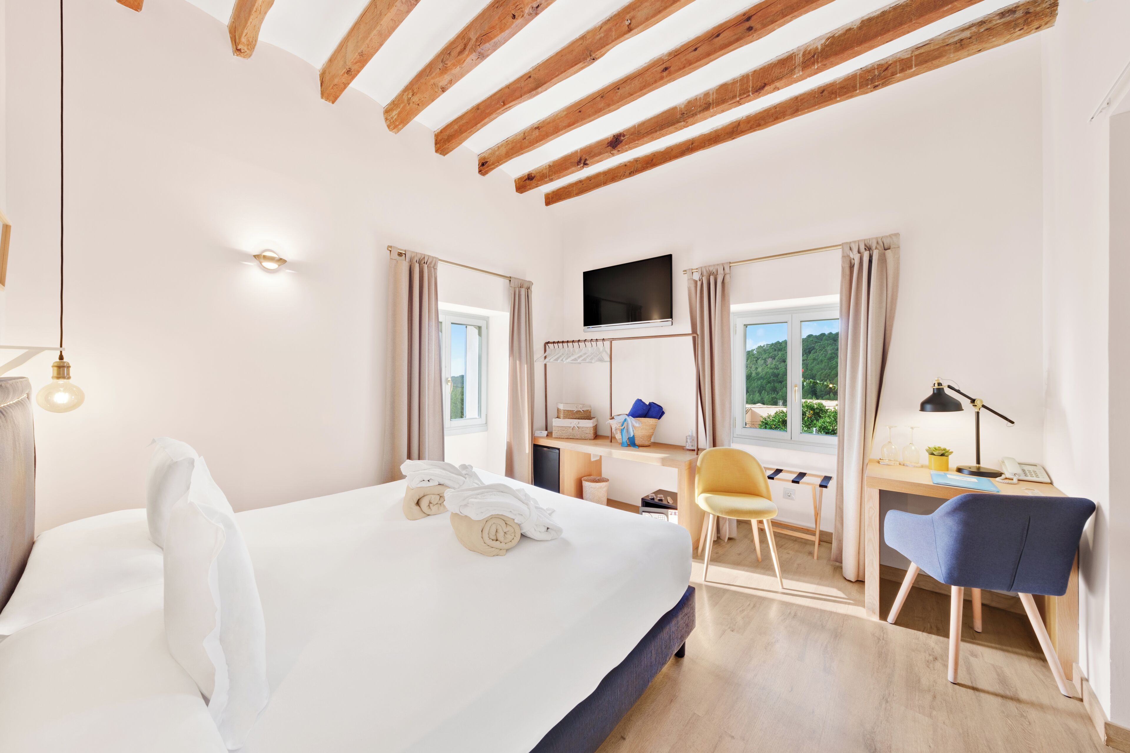 Habitación de hotel con cama, escritorio, silla y televisión.