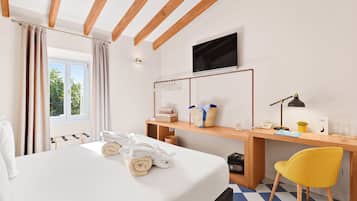 A hotel room with a bed, a desk, a chair, a TV, and a window with curtains.