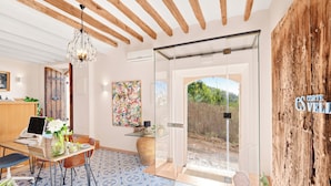 A modern interior with a glass door leading outside, a wooden ceiling, and a dining area with a laptop and flowers. - Es Corte Vell - Inland Bunyola - Adults Only (Bunyola)