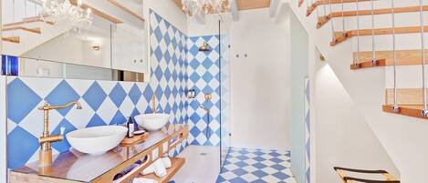 A modern bathroom with a checkered floor, a glass sink, and a wooden vanity.