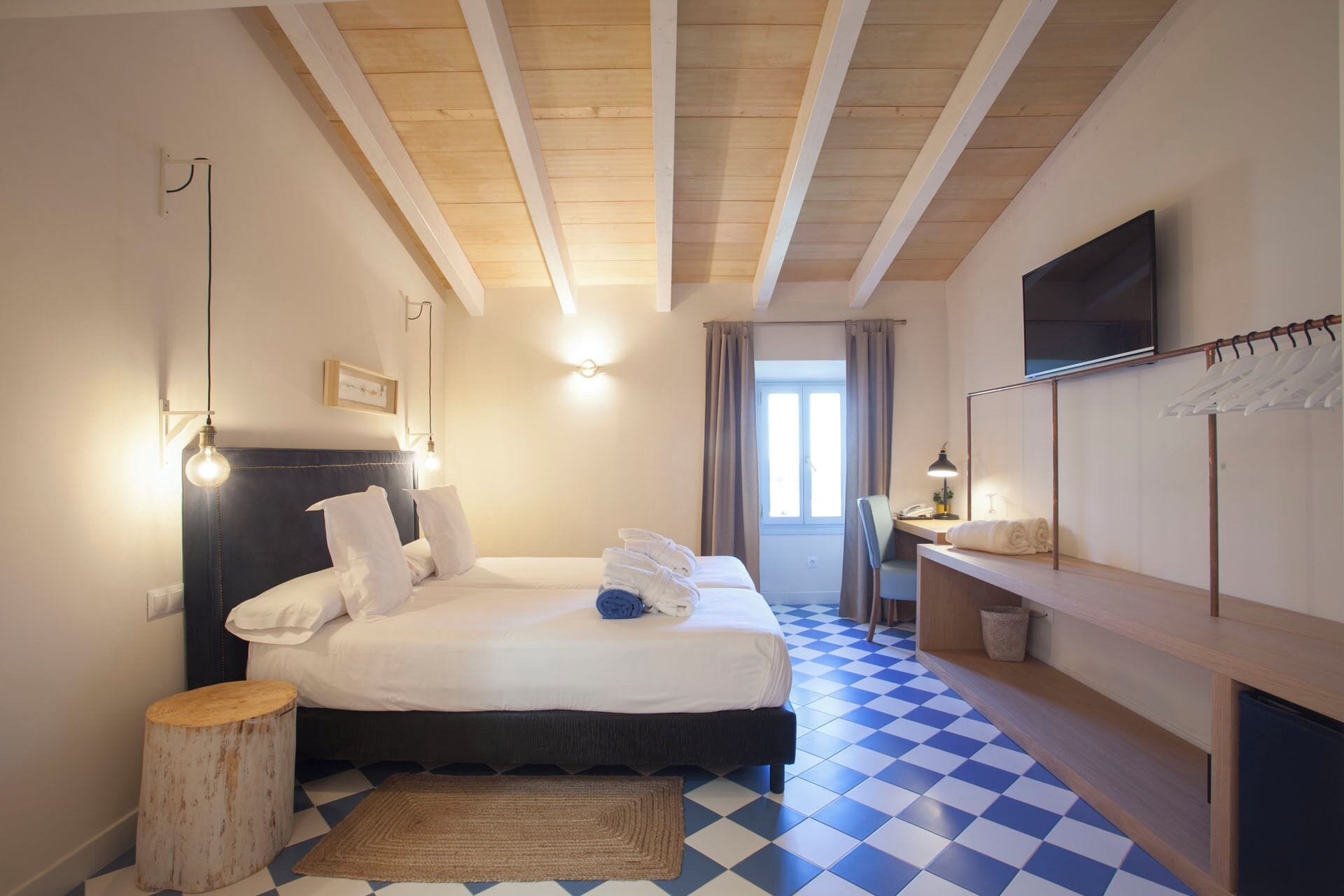 A bedroom with a bed, bedside table, lamp, and a TV mounted on the wall.