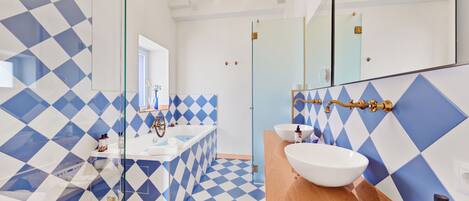 A modern bathroom with a geometric tile pattern, a large mirror, and a wooden vanity.