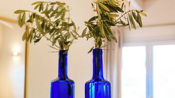 Two blue vases with green plants on a bedside table in a hotel room.